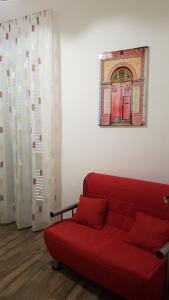 een rode bank in een woonkamer met een schilderij aan de muur bij La Volta in Noto