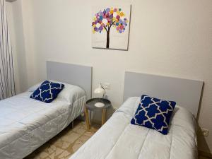 una camera con due letti e un quadro di un albero sul muro di Apartamento Plaza del Oeste con cuatro habitaciones a Salamanca