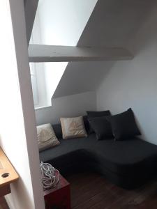 a black couch with pillows in a room at L'Ancienne Forgerie de Sainte mère Eglise in Sainte-Mère-Église