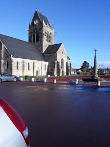 a church with a car parked in front of it at L'Ancienne Forgerie de Sainte mère Eglise in Sainte-Mère-Église