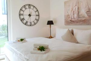 a white bed with towels and a clock on the wall at Baabe Villen Ensemble FeWo 02 Kais in Baabe