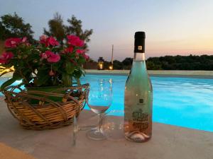 a bottle of wine and two glasses next to a pool at Villa Lucia With Salt Pool in Fontane Bianche