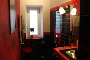 a bathroom with a red and black tiled wall at Apartamenty Gołębia 3 in Krakow