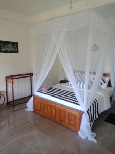a bedroom with a canopy bed with white curtains at Royal Vantage in Ella