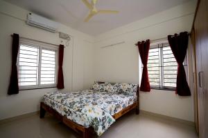 a bedroom with a bed and two windows at Castle JP Service Apartments in Bangalore