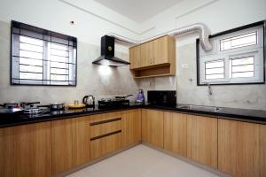 eine Küche mit Holzschränken und schwarzen Arbeitsplatten in der Unterkunft Castle JP Service Apartments in Bangalore