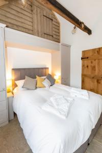 a large white bed in a bedroom with wooden ceilings at The Yard @ Pringle Farm in Great Stukeley