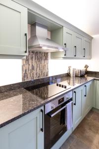 a kitchen with white cabinets and a stove top oven at The Yard @ Pringle Farm in Great Stukeley