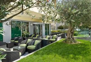 a patio with black chairs and a tree at Hotel Madison - Cattolica in Cattolica