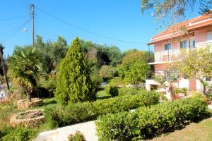 un jardin en face d'un bâtiment avec des arbres et des buissons dans l'établissement Maria's Paradise, à Astrakeri