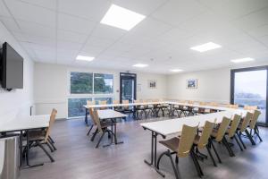 a classroom with tables and chairs and windows at Centre Jean XXIII in Annecy