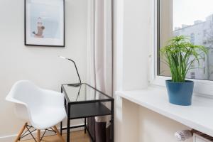 einen weißen Stuhl und einen Tisch in einem Zimmer mit Fenster in der Unterkunft Family City Center Apartments by Renters in Warschau