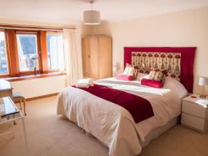 a bedroom with a large bed with a red headboard at The Flat In The Square in Helensburgh