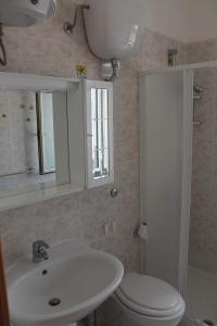 een badkamer met een wastafel, een toilet en een spiegel bij Villetta Leo in Baia Verde in Il Monte