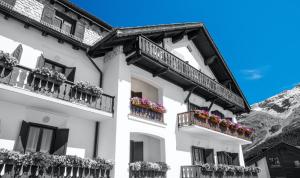 un edificio bianco con balconi e fiori di Giardino Bed & Breakfast a Silvaplana