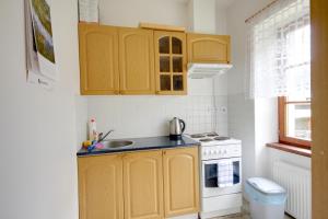 a kitchen with yellow cabinets and a sink and a stove at Pension U Háčků in Harrachov