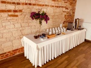 a long white table in a room with a brick wall at Arka Agroturyska in Kosin