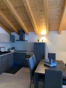 una cucina con soffitto in legno, tavolo e sedie di Alpin Sky a Temù