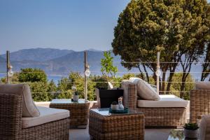 - une terrasse avec des tables et des chaises en osier dans l'établissement Hotel Scandola, à Piana