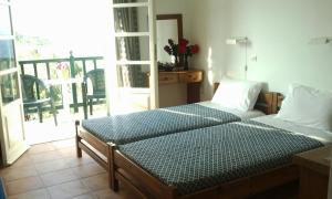 a bedroom with two beds and a balcony at Dionisis Studios in Város