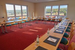 a room with long tables and chairs and windows at Berghotel Tambach in Tambach-Dietharz