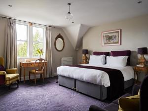 a hotel room with a large bed and a desk at Cotswold Grange in Cheltenham