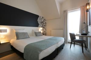 a hotel room with a large bed and a desk at Martin's Brugge in Bruges