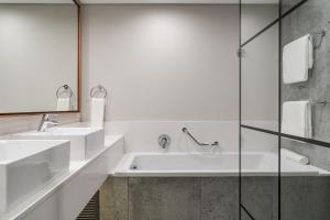 a bathroom with a tub, sink and mirror at Protea Hotel by Marriott Kruger Gate in Skukuza