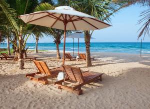 a group of chairs and an umbrella on a beach at Cardamon Hotel Nilaveli in Nilaveli