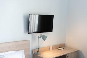 a tv hanging on a wall above a bed at Hotel Aria in Nice