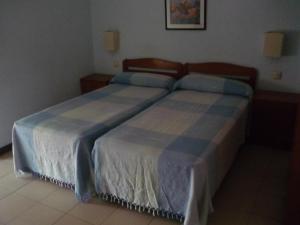 1 dormitorio con 2 camas con sábanas azules y blancas en Hostal El Centro, en Huesca