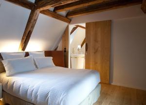 - une chambre avec un lit blanc et des poutres en bois dans l'établissement Hotel Les Haras, à Strasbourg