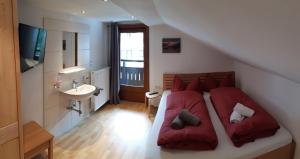 una camera da letto con un letto con cuscini rossi e un lavandino di Haus Hell a Mayrhofen