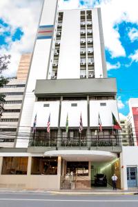 een hoog wit gebouw met vlaggen ervoor bij Hotel Dan Inn São José do Rio Preto in Sao Jose do Rio Preto