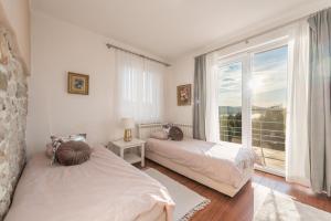 a bedroom with two beds and a large window at Villa Rosa in Pašman