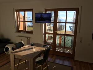 sala de estar con mesa y TV en la pared en Ferienwohnung Seebruck am Chiemsee en Seebruck