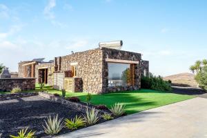 ein Steinhaus mit grünem Rasen in der Unterkunft Villa Tranquila in Villaverde