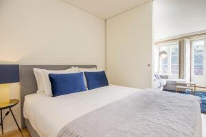 een slaapkamer met een groot wit bed met blauwe kussens bij São Bento Hill View in Porto