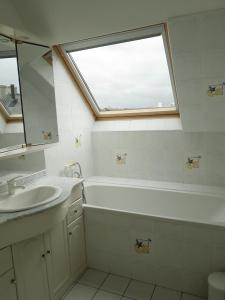 baño con bañera, lavabo y ventana en Le Prat - Santec en Santec