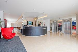 a lobby with a bar and a red chair at Slim Curitiba João Bettega in Curitiba