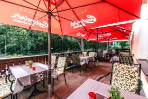 un patio con mesas y sombrillas rojas en un restaurante en Historische Spitzgrundmühle en Coswig