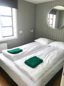 a white bed with two green towels on it at Sólbakki Holiday Home in Egilsstaðir