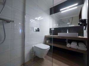 a bathroom with a toilet and a sink and a mirror at Brassel Aparthotel in Wrocław