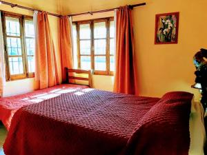 1 dormitorio con 1 cama roja y 2 ventanas en Cabañas Calderón II en San Rafael