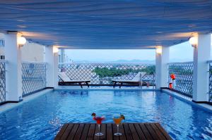 a swimming pool with two drinks on a balcony at Moonlight Hotel Hue in Hue
