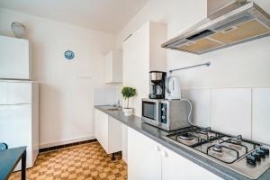 uma cozinha com armários brancos e um forno com placa de fogão em Lucky Lambert Apartment em Antuérpia