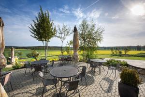 a patio with tables and chairs and an umbrella at Penzion Blanský Les in Dubné