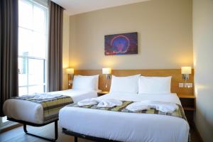 a hotel room with two beds and a window at Kings Cross Inn Hotel in London