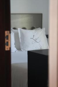 a bed with white pillows on top of it at Lazza Hotel in Figueira da Foz