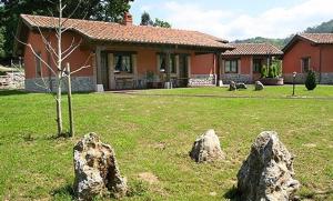 a house with rocks in front of a yard at Apartamentos Rurales La Granda in Cangas de Onís